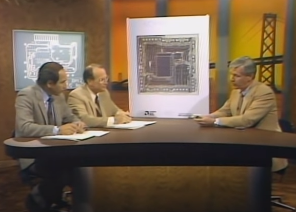 Phil Dowling shows a blown-up image of the AMD Am29116 microprocessor to Stewart Cheifet and Herbert Lechner.