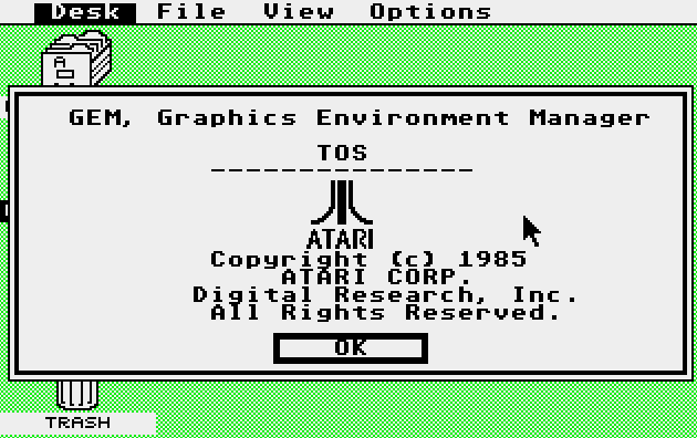 An emulated version of the original Atari 520ST desktop environment. There is a green background with icons for the floppy disk drive and trash; a top-bar menu with options for Desk, File, View, and Options; and an open window displaying the following system information: “GEM, Graphics Environment Manager, TOS, Atari, Copyright 1985 Atari Corp., Digital Research, Inc., All Rights Reserved.