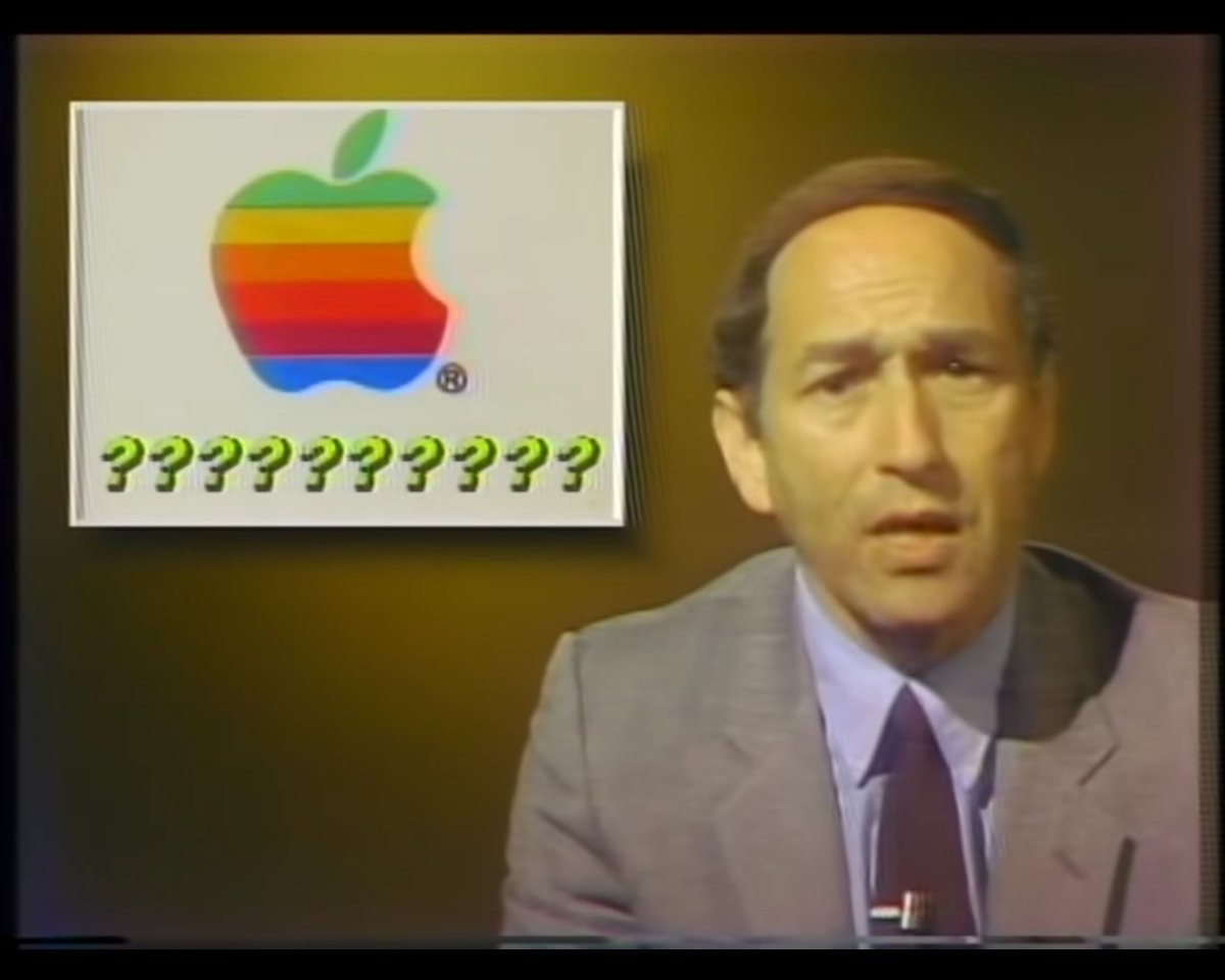 Stewart Cheifet presenting a news story about Apple Computers. In the top right corner is a box with the old six-color Apple logo and a bunch of question marks, “??????????