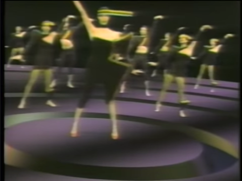 A group of female dancers performing on a computer-generated stage.